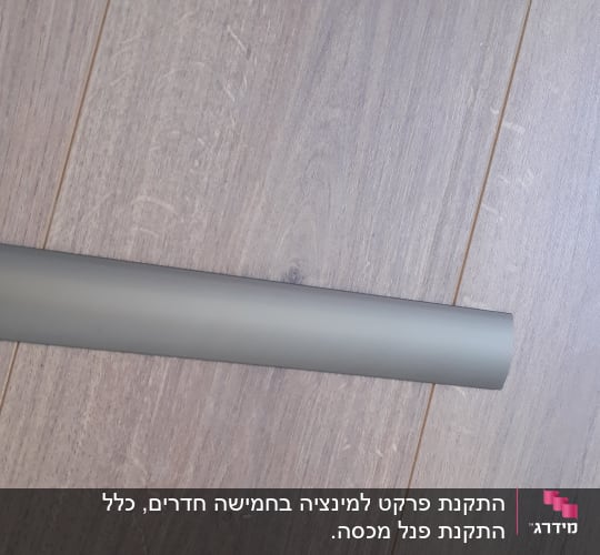 רצפת פרקט עץ עם מוט אפור מונח עליה